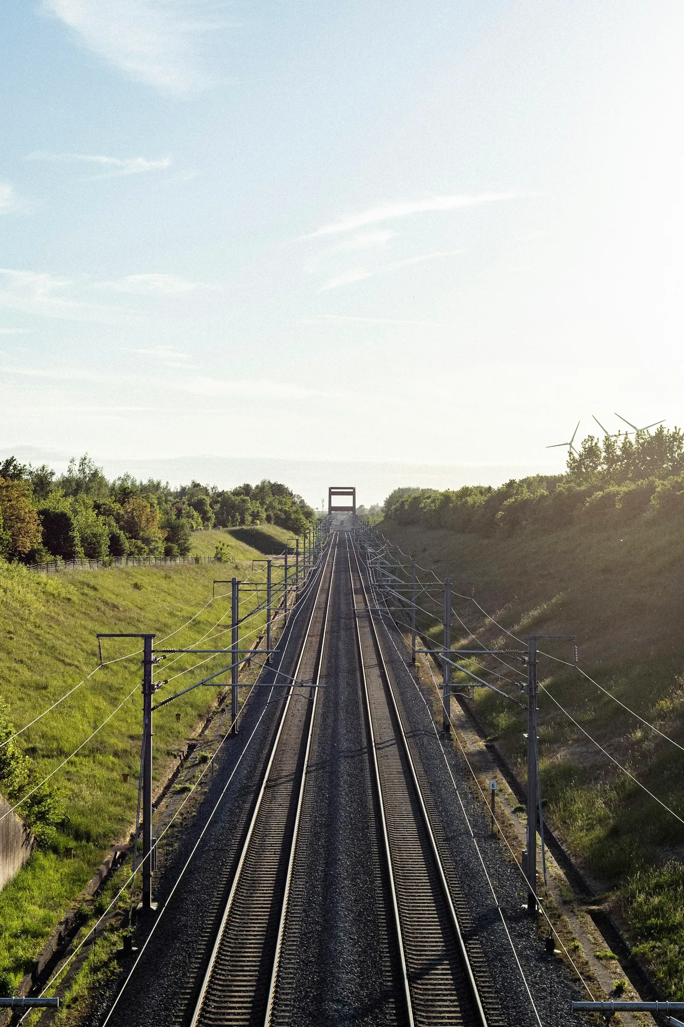 Electrified railway line running through green embankments